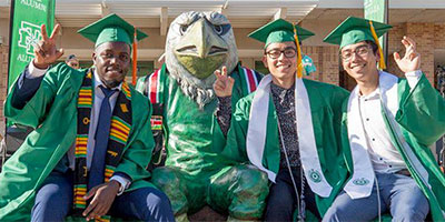 Graduates sitting with UNT Mascot Scrappy